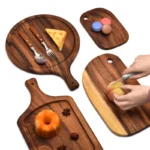 Acacia wood cutting board with bread and cheese on a wooden table