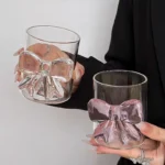 Cute pink bow tie glass cup filled with pink juice on a table