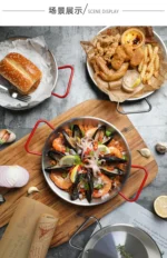 Stainless steel paella pan with double ears on a stove