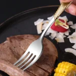 Elegant gold flatware set with steak knife, fork, and spoon on a dark table