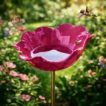 Handcrafted red poppy flower bird bath garden stake with metal stem, standing in a sunny garden bed.