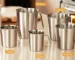 Stainless steel measuring cup with inner scale markings on a kitchen counter