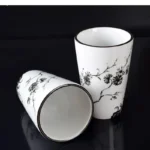 Mouthwash cup with a blue floral pattern, sitting on a glass shelf in a modern bathroom.