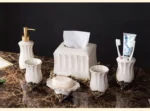 Soap dispenser with a porcelain body and gold pump, in a bright bathroom setting.