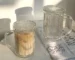 Set of transparent glass coffee mugs with lids and straws on a wooden table