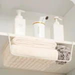 Metal under shelf basket hanging from a kitchen shelf, holding spices and small jars