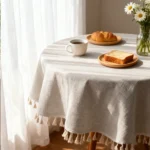 Round linen tablecloth with tassels on a dining table
