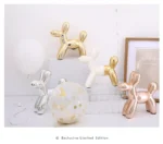 Gold balloon dog on a kitchen counter with a fruit bowl.