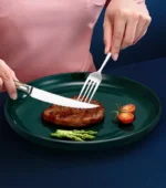 Elegant gold flatware set with steak knife, fork, and spoon on a dark table