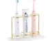 White resin electric toothbrush holder with 3 slots on a marble bathroom countertop.