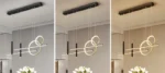 Three black pendant lights at different heights over a dining table.