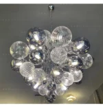 Smoky gray chandelier with glass bubbles hanging over a modern dining table