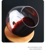 Rotating whiskey glass on a wooden table with amber liquid swirling inside