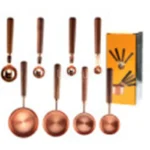 Set of stainless steel measuring cups with copper and rose gold finishes on wooden stand