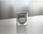 Clear double wall insulated glass mug with espresso coffee on wooden table
