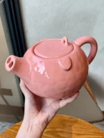 Funny pig teapot pouring tea from its snout on a kitchen counter