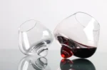 Rotating whiskey glass on a wooden table with amber liquid swirling inside
