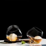 Rotating whiskey glass on a wooden table with amber liquid swirling inside
