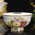 Elegant bone china dinnerware set with plates, bowls, and soup spoons on a wooden table