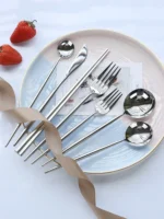 Elegant stainless steel flatware set with forks, spoons, and knives arranged on a wooden table