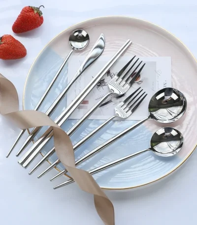 Elegant stainless steel flatware set with forks, spoons, and knives arranged on a wooden table