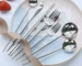 Elegant stainless steel flatware set with forks, spoons, and knives arranged on a wooden table