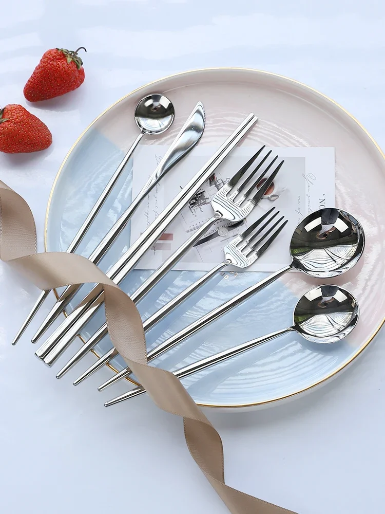 S1ab3492871074fa593041f83572a319bu.webp Elegant stainless steel flatware set with forks, spoons, and knives arranged on a wooden table