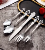 Gold flatware set with spoon, fork, and steak knife on a white tablecloth