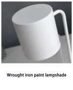 The lamp's base and stem detail, brushed metal finish, on a modern office desk.