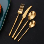 Matte gold flatware set with antique finish arranged on a wooden table
