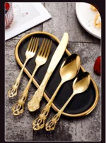 Gold flatware set with spoon, fork, and steak knife on a white tablecloth