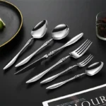 Elegant French stainless steel cutlery set with pointed tail handles on a wooden table