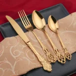 Gold flatware set with spoon, fork, and steak knife on a white tablecloth