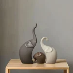 Set of three ceramic elephants in graduated sizes arranged on a wooden office desk.