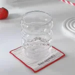 Set of glass cups with straws on a wooden table, filled with iced tea and lemon