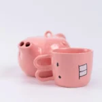 Funny pig teapot pouring tea from its snout on a kitchen counter