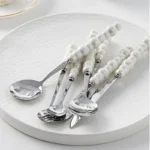 Stainless steel flatware set with ceramic pearl handles on wooden table