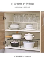 Adjustable dish drying rack with multiple tiers holding plates, bowls, and spice jars on a kitchen counter
