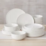 Elegant ceramic plates set with dinner plates, dessert plates, cereal bowls, and soup bowls arranged on a wooden table