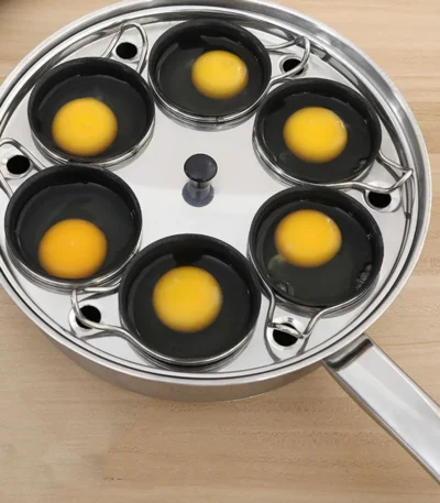 Stainless steel egg poacher with three cups on a stovetop, steaming eggs