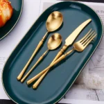 Matte gold flatware set with antique finish arranged on a wooden table