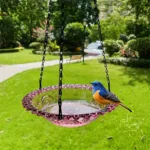 Garden bird bath tray with a blue bowl, suspended from a wooden beam in a backyard.