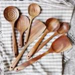 Wooden cooking utensils set with spatula, soup ladle, and rice scoop on a kitchen counter