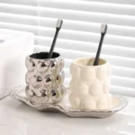 Luxury electroplated ceramic mug set for couples, two toothbrush cups in metallic finish on bathroom counter.