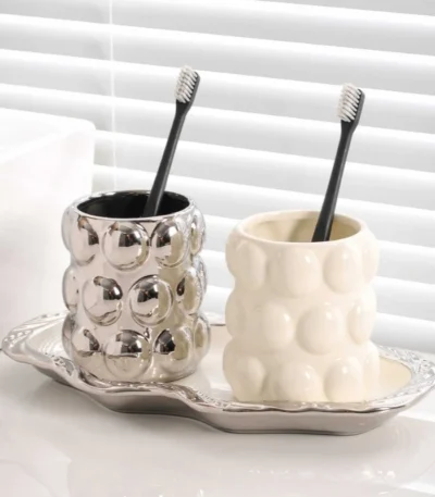 Luxury electroplated ceramic mug set for couples, two toothbrush cups in metallic finish on bathroom counter.