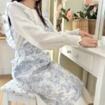Woman wearing a cotton apron for baking with fresh plaid pattern and ruffled edges in a rustic kitchen