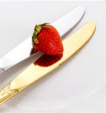 Gold flatware set with spoon, fork, and steak knife on a white tablecloth