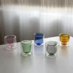 Clear double wall insulated glass mug with espresso coffee on wooden table