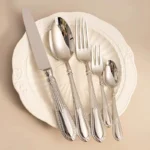 Elegant stainless steel flatware set with mirror finish arranged on a wooden table