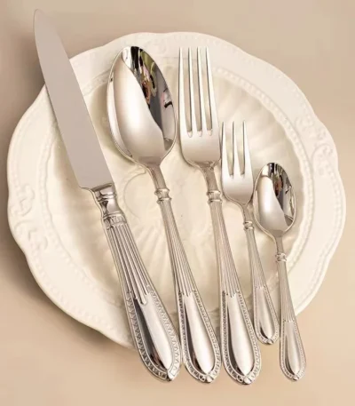 Elegant stainless steel flatware set with mirror finish arranged on a wooden table
